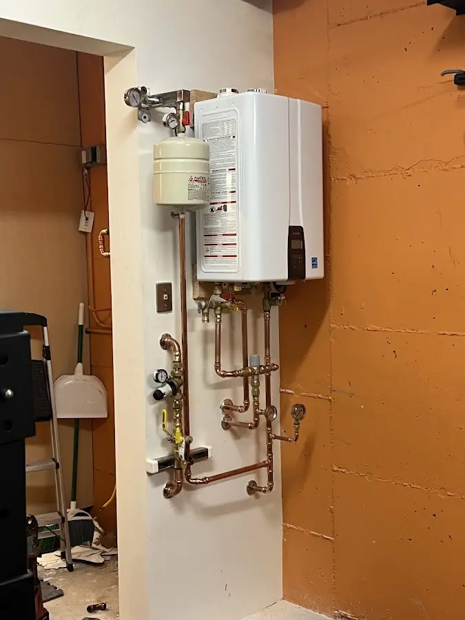 Plumbing technician inspecting water heater connections in Durham